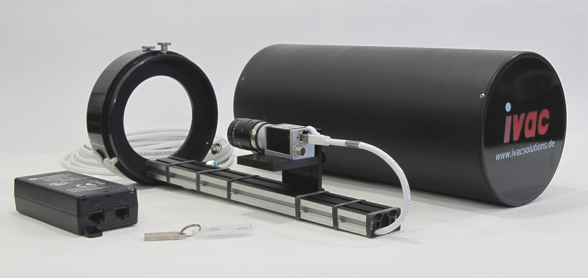 Photograph of the standard scope of delivery of an iRHEED system, including camera with lens, camera mount, hard and soft cover for the camera mount, connection cables, power-over-ethernet supply and USB stick with software